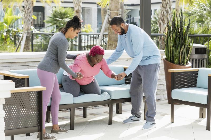A doula assists a pregnant woman while her husband supports her.