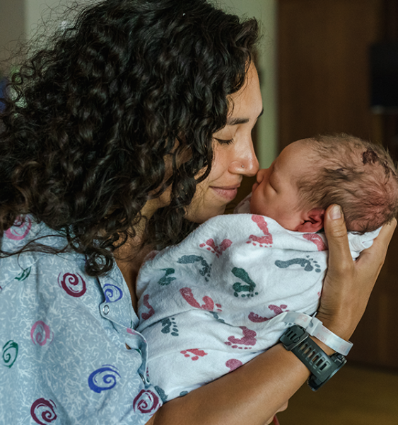 A mother holds her newborn baby in a hospital shortly after birth.