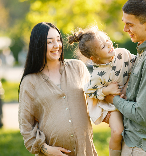 A pregnant mother plays with her older daughter and husband.