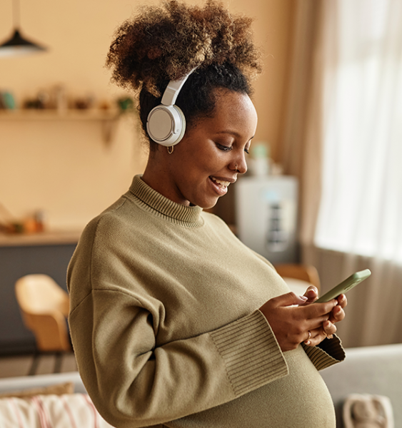 A pregnant woman uses her cell phone to attend a telehealth appointment with her doula.